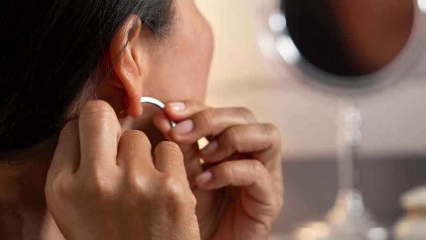 Woman putting on earrings